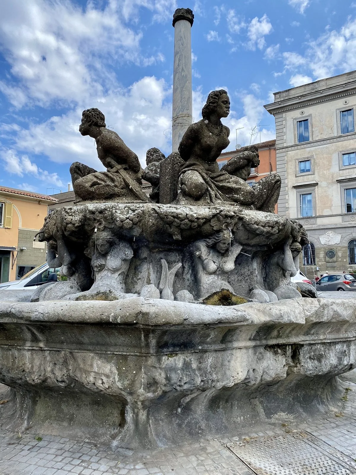 La Fontana dei Quattro Mori a Marino, con le statue in pietra attorno alla colonna centrale e gli edifici della piazza sullo sfondo